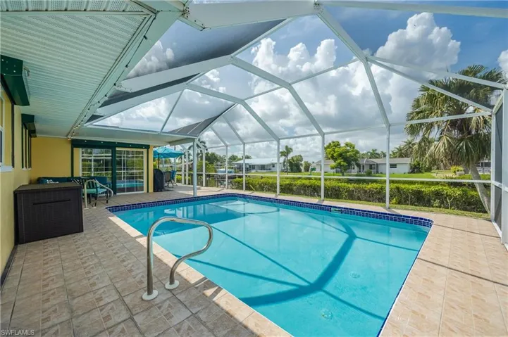 View of pool with glass enclosure and a patio area