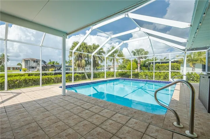 View of swimming pool with glass enclosure and a patio