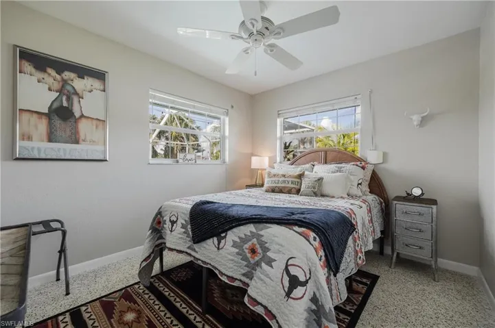 Carpeted bedroom with ceiling fan and multiple windows