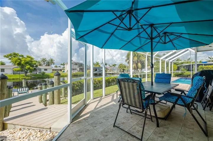 View of patio / terrace with a dock, glass enclosure, and a water view