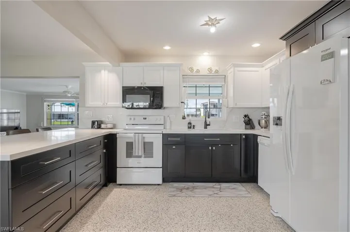 Kitchen featuring white cabinets, plenty of natural light, backsplash, and white appliances