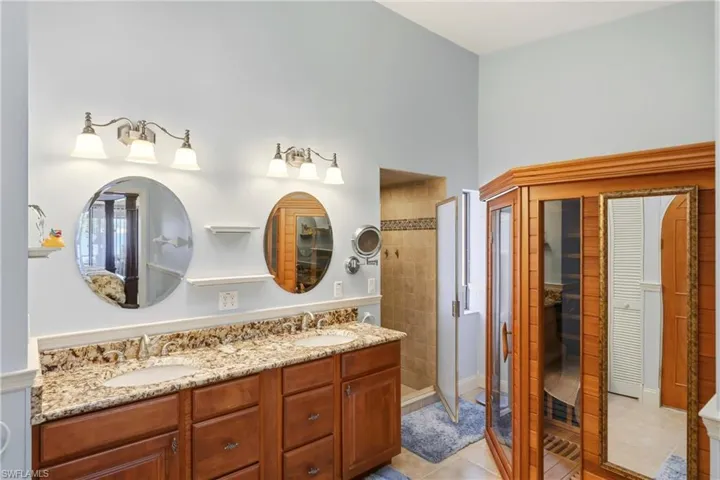 Bathroom featuring a sauna / steam room, double vanity, a stall shower, and light tile patterned floors