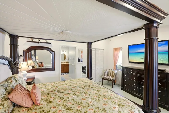 Bedroom with connected bathroom, light colored carpet, and a closet