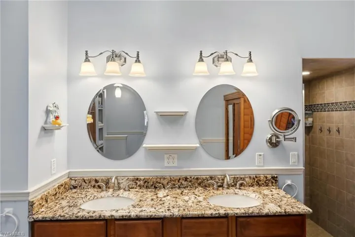 Full bath featuring double vanity and tiled shower