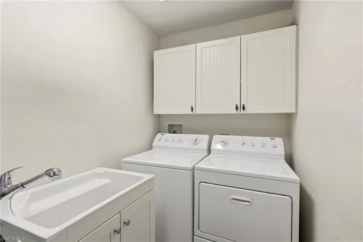 Laundry room featuring cabinet space, a textured wall, and washing machine and clothes dryer