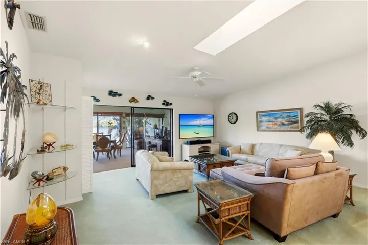 Living area with a skylight, carpet floors, and ceiling fan