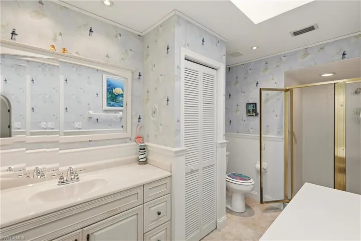 Full bathroom with recessed lighting, a stall shower, vanity, wallpapered walls, and a wainscoted wall