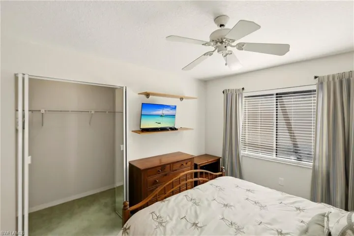 Carpeted bedroom with a closet, a ceiling fan, and a textured ceiling
