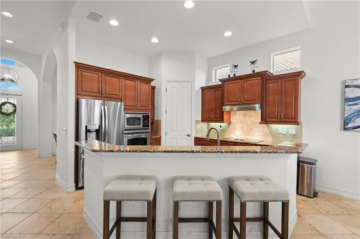 Kitchen with visible vents, stainless steel appliances, under cabinet range hood, a breakfast bar area, and backsplash