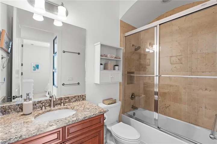 Bathroom with enclosed tub / shower combo, toilet, and vanity