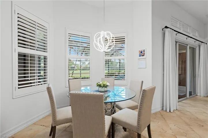 Dining room with baseboards, an inviting chandelier, and stone tile floors