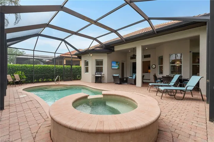 View of pool featuring a pool with connected hot tub, a patio, glass enclosure, ceiling fan, and a grill