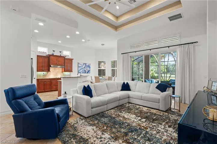 Living room featuring a high ceiling, recessed lighting, ceiling fan, and visible vents
