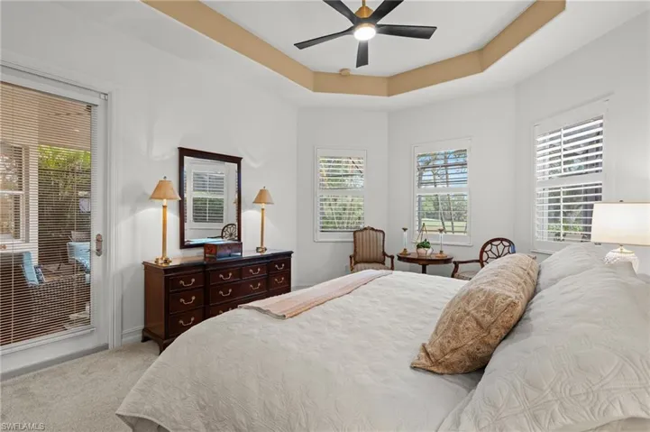 Bedroom with multiple windows, a tray ceiling, carpet, and ceiling fan