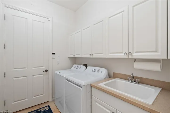 Washroom featuring cabinet space, a sink, and independent washer and dryer