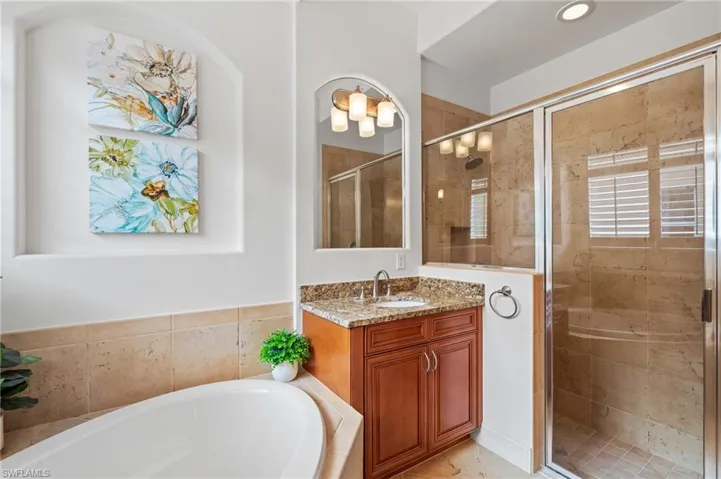 Bathroom featuring a shower stall, a bath, and vanity