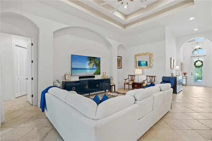 Living area featuring arched walkways, a towering ceiling, baseboards, and recessed lighting