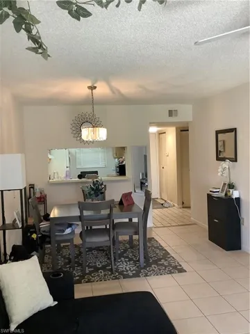 Dining space with light tile patterned floors, a textured ceiling, and a chandelier