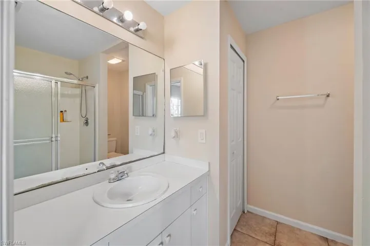 Bathroom featuring toilet, an enclosed shower, vanity, and tile patterned floors