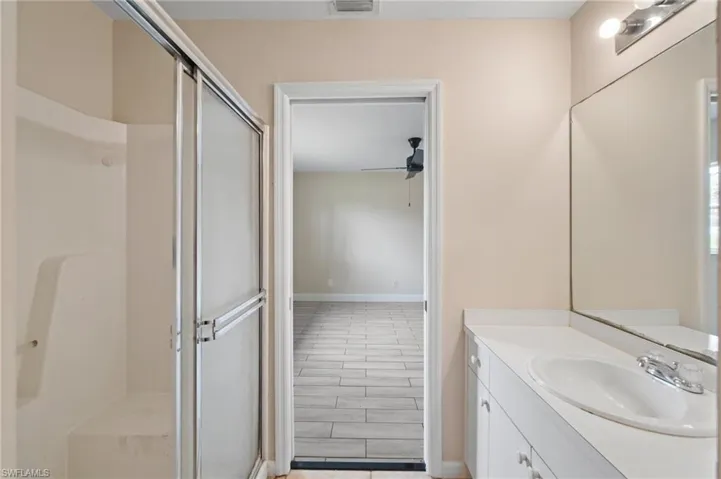Bathroom with vanity, hardwood / wood-style flooring, ceiling fan, and a shower with door