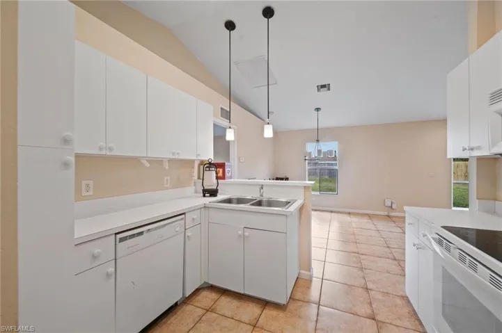 Kitchen with lofted ceiling, white cabinets, and white appliances