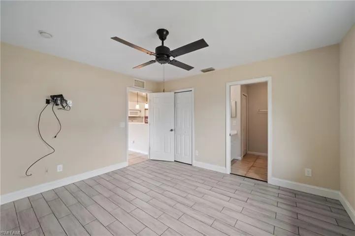 Unfurnished bedroom featuring ensuite bath, light wood-type flooring, and ceiling fan