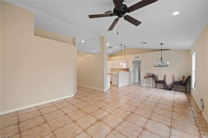 Unfurnished living room featuring lofted ceiling, ceiling fan with notable chandelier, and light tile patterned floors