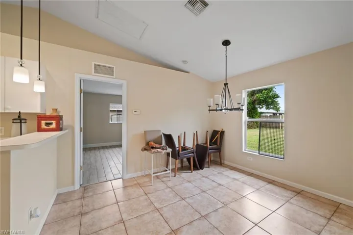 Tiled dining room with lofted ceiling and a chandelier