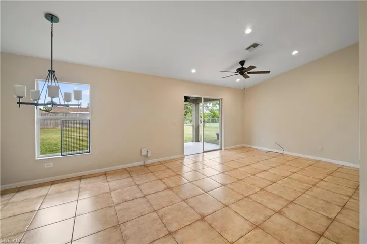 Tiled spare room with ceiling fan with notable chandelier