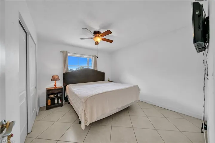 Bedroom with light tile patterned floors, a ceiling fan, and a closet