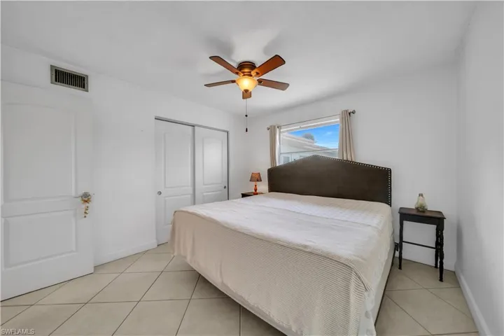 Bedroom with light tile patterned floors, a closet, and a ceiling fan