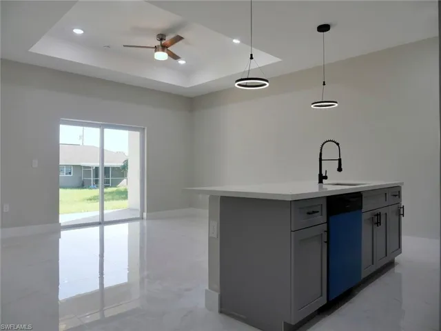 Spacious living area featuring a tray ceiling with recessed lighting and a ceiling fan