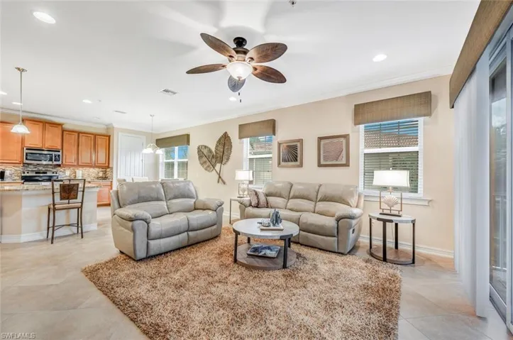 Tiled living room with ceiling fan and ornamental molding