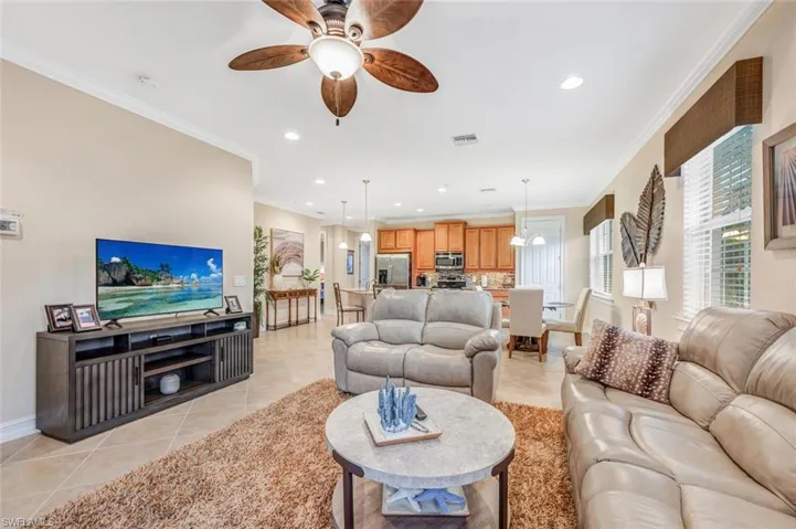 Living room with ceiling fan, crown molding, and light tile patterned floors