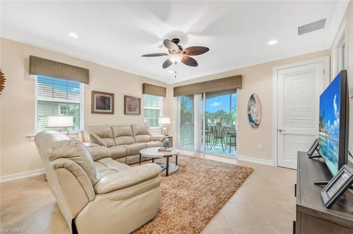 Tiled living room featuring ceiling fan and ornamental molding