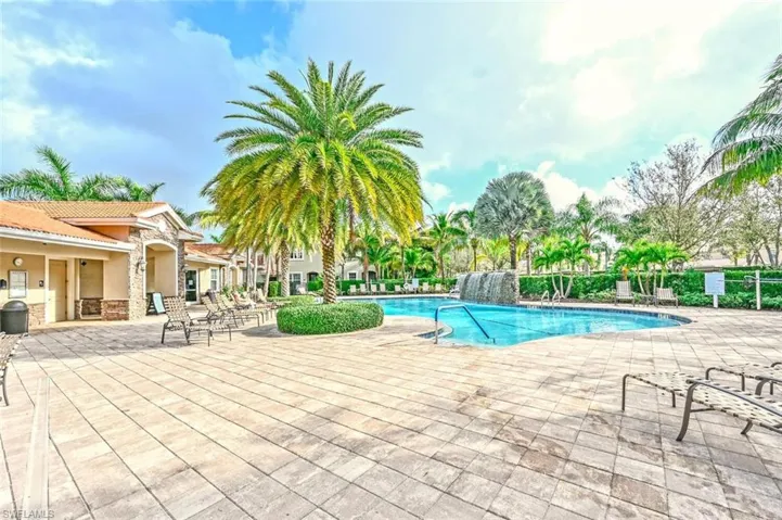 View of community pool with a patio area and pool water feature