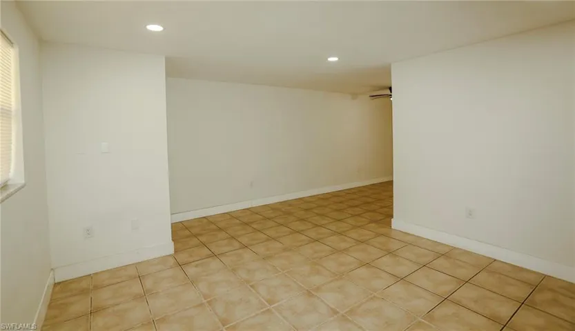 Spacious room featuring neutral-toned tile flooring, recessed ceiling lighting, and a window with blinds