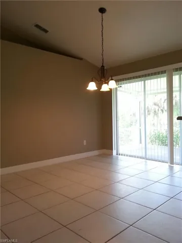 Tiled spare room featuring an inviting chandelier