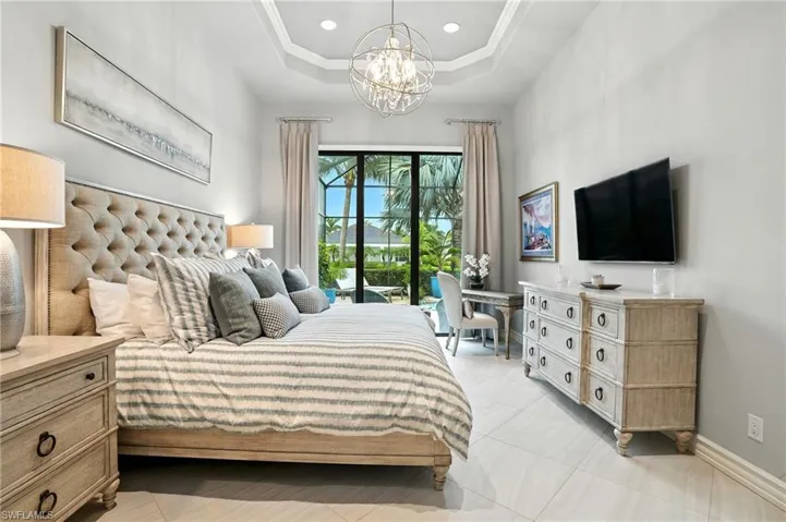 Bedroom featuring a raised ceiling, light tile patterned flooring, recessed lighting, a chandelier, and access to exterior