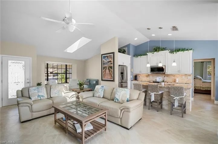 Living room featuring a ceiling fan, lofted ceiling, and a skylight