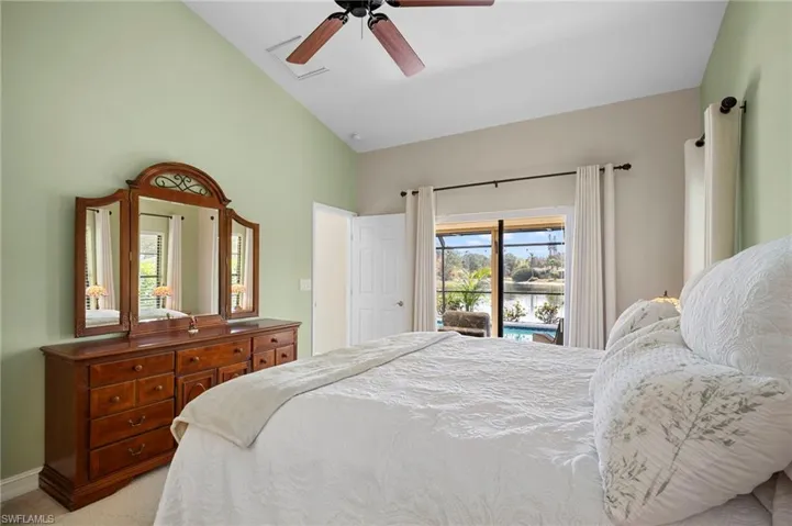 Bedroom featuring vaulted ceiling, light carpet, ceiling fan, and access to outside