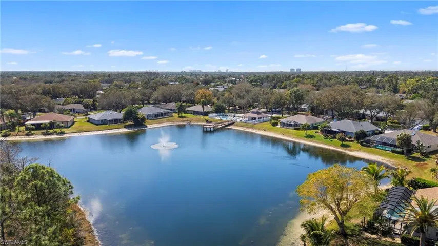 Aerial perspective of suburban area featuring a large body of water and a tree filled landscape