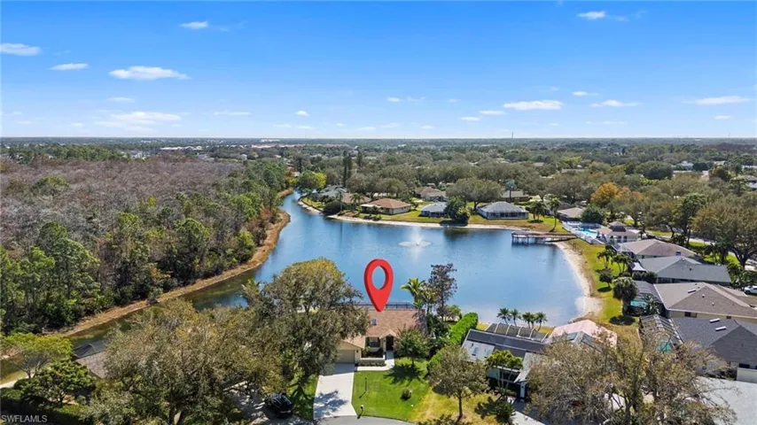 Aerial perspective of suburban area featuring a large body of water and a tree filled landscape