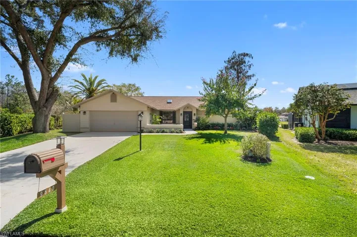 Ranch-style home with concrete driveway, stucco siding, a front lawn, and an attached garage