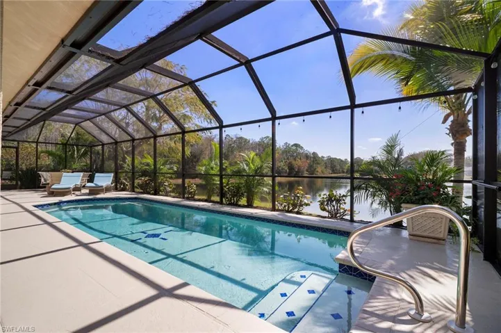 Swimming pool featuring a sunroom, a water view, glass enclosure, and a patio