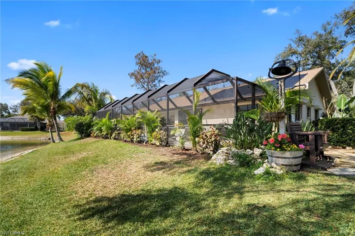 View of green lawn with a sunroom, a lanai, and a water view