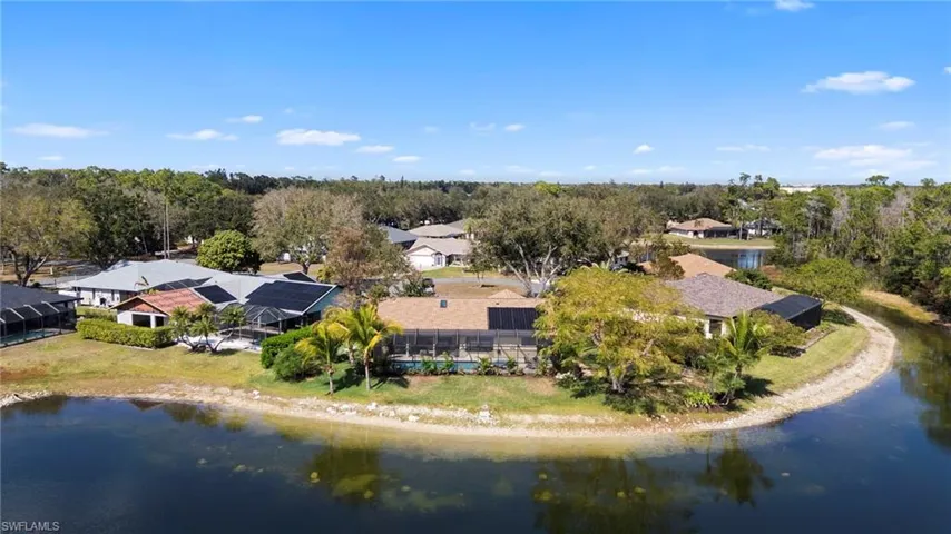 Drone / aerial view of a nearby body of water and a tree filled landscape