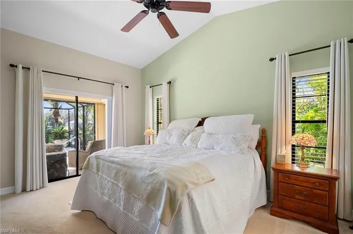 Bedroom with light carpet, access to exterior, vaulted ceiling, and ceiling fan