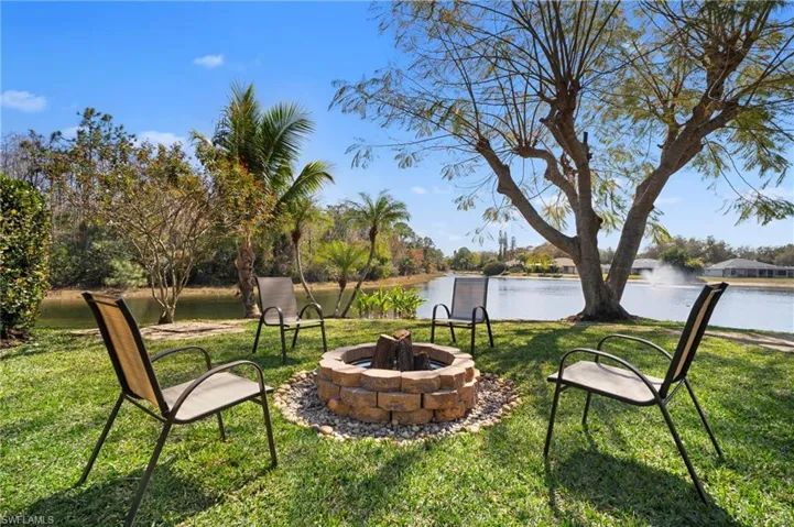 View of green lawn featuring an outdoor fire pit and a water view