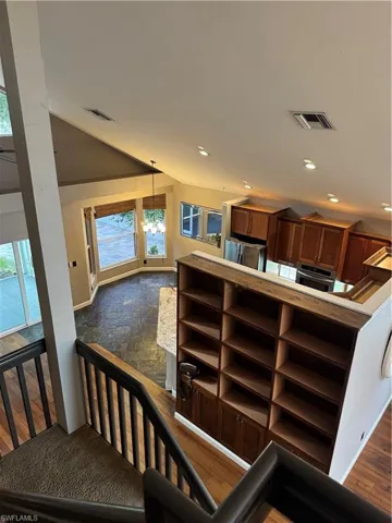 Staircase with vaulted ceiling, wood finished floors, and a chandelier